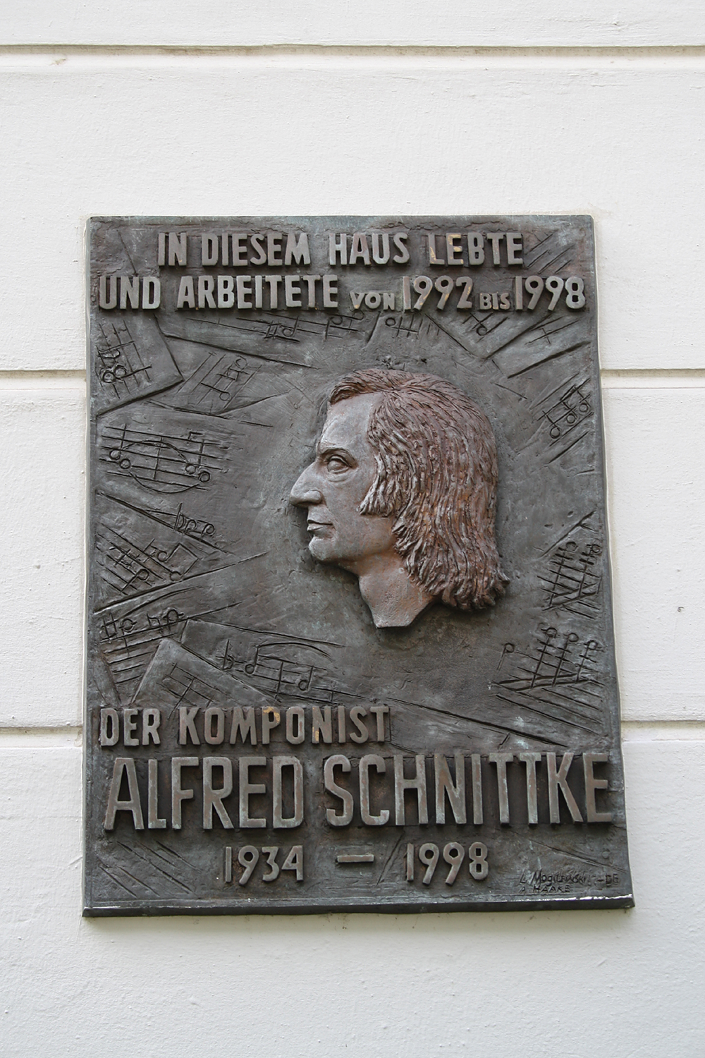 Alfred Schnittke. Artikel von Christian Erdmann. Bild: Tafel am ehemaligen Wohnhaus des Komponisten in Hamburg.